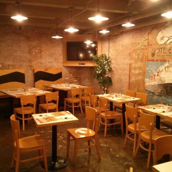 Cozy restaurant interior with exposed brick walls, wooden tables and chairs, and a large mural.