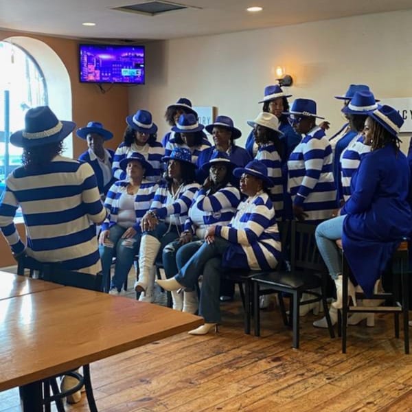 Group of women in blue and white striped shirts and blue hats gathered in a restaurant.