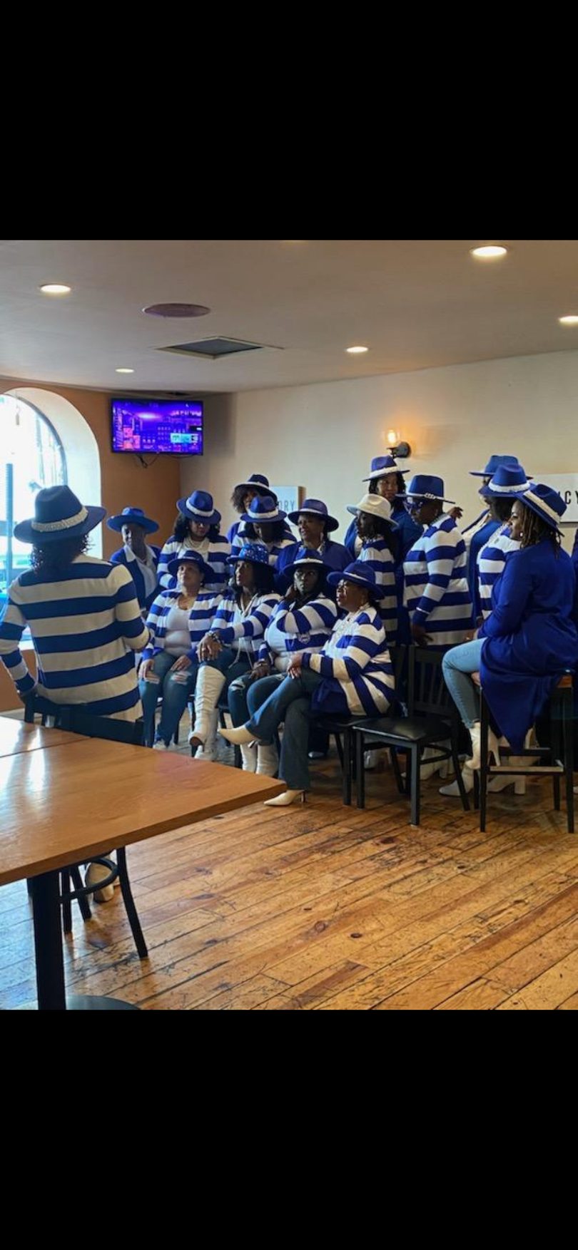 Group of women in blue and white striped shirts and blue hats gathered in a restaurant.