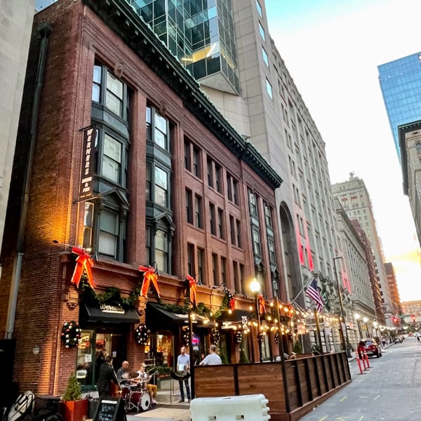A brick building with a restaurant, outdoor patio, and live band on a city street.