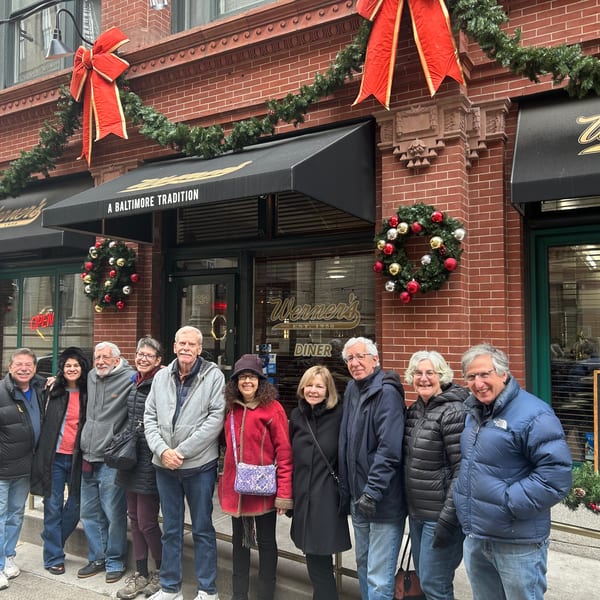Group of people smiling in front of Werner's Diner, decorated for Christmas with wreaths and garlands.