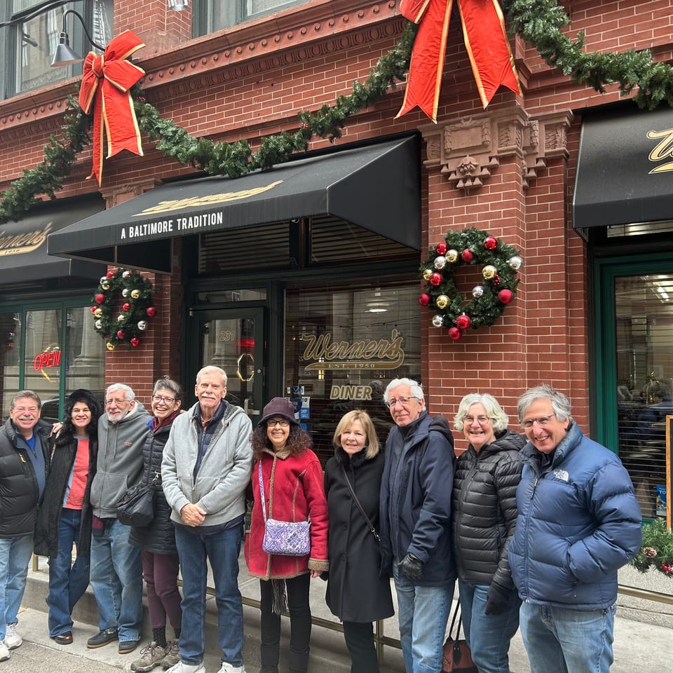 Group of people smiling in front of Werner's Diner, decorated for Christmas with wreaths and garlands.
