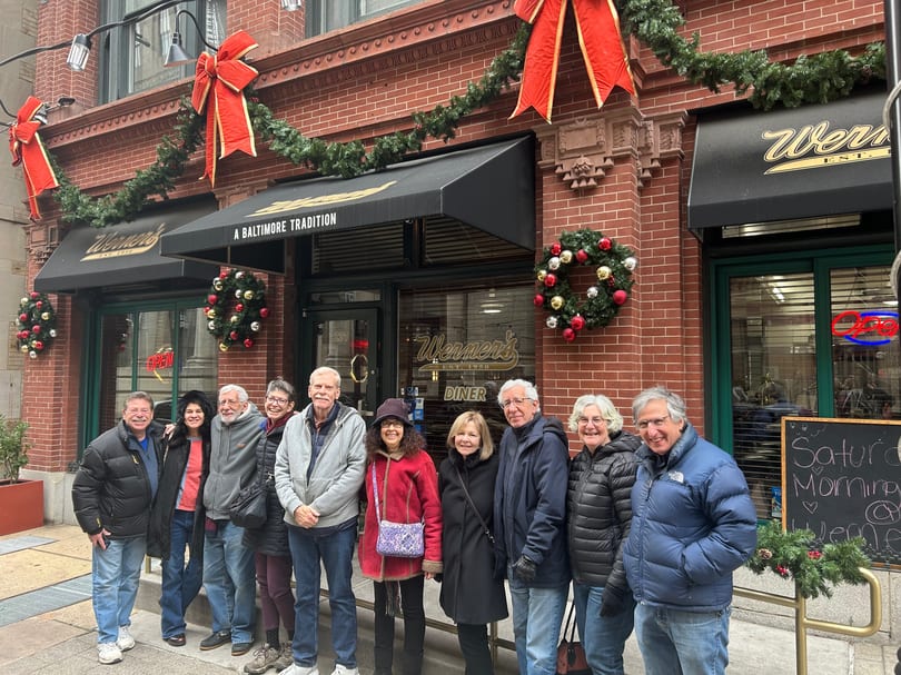Group of people smiling in front of Werner's Diner, decorated for Christmas with wreaths and garlands.