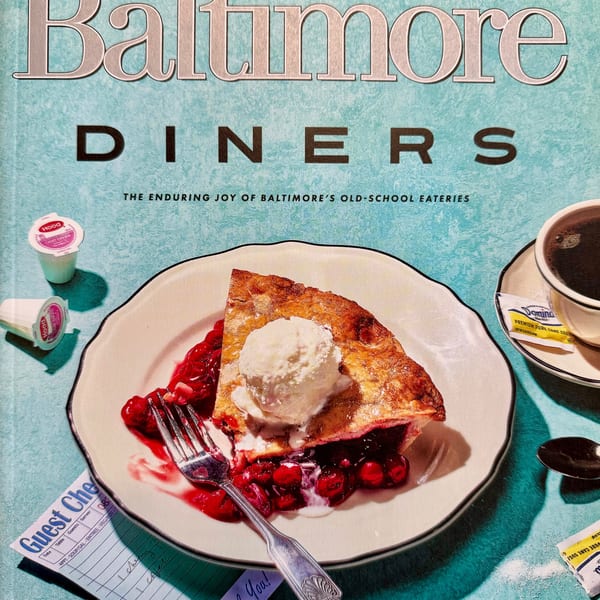 A slice of cherry pie with vanilla ice cream, a fork, coffee, and a diner check on a magazine cover.