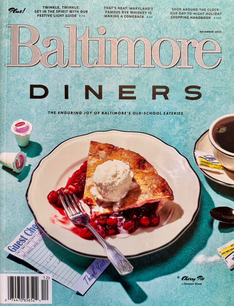 A slice of cherry pie with vanilla ice cream, a fork, coffee, and a diner check on a magazine cover.