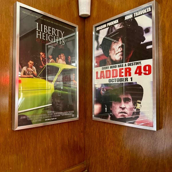 Two movie posters, "Liberty Heights" and "Ladder 49," displayed on a wooden wall corner.