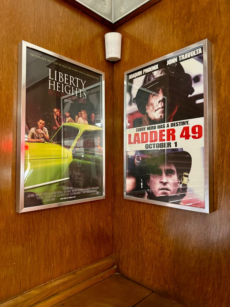 Two movie posters, "Liberty Heights" and "Ladder 49," displayed on a wooden wall corner.