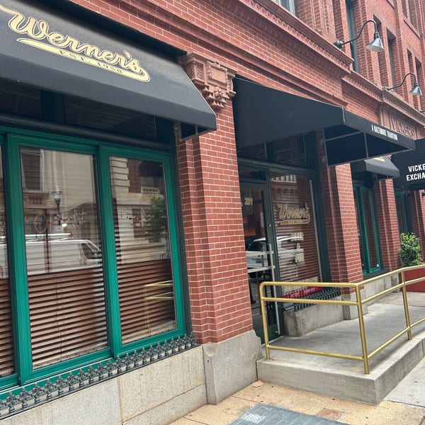 Werner's restaurant storefront with black awnings, green window frames, and a gold handrail leading to the entrance.