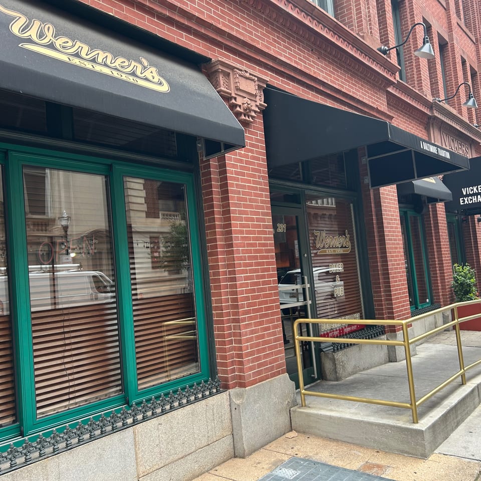 Werner's restaurant storefront with black awnings, green window frames, and a gold handrail leading to the entrance.