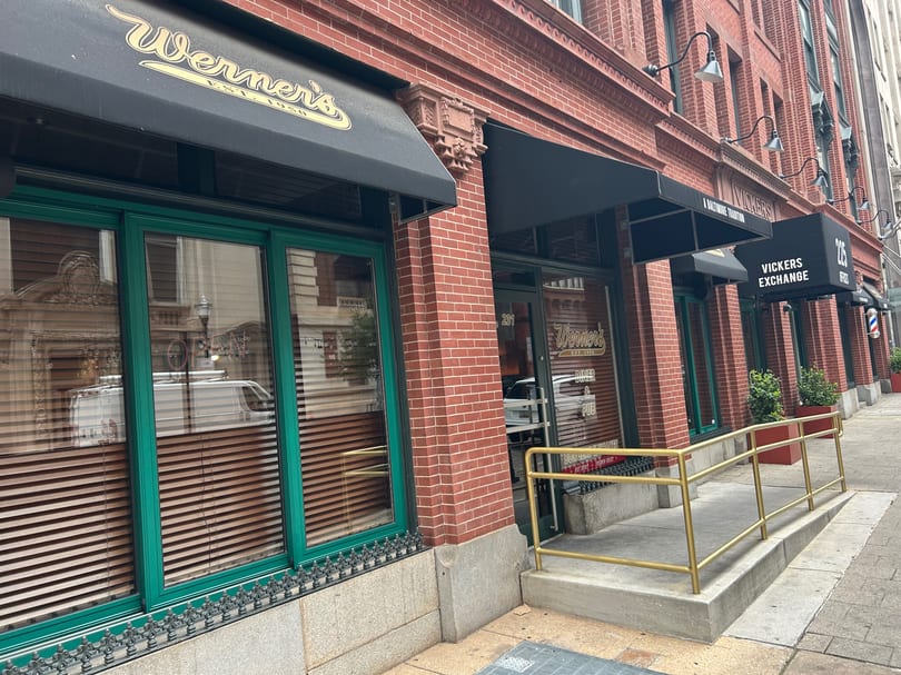 Werner's restaurant storefront with black awnings, green window frames, and a gold handrail leading to the entrance.